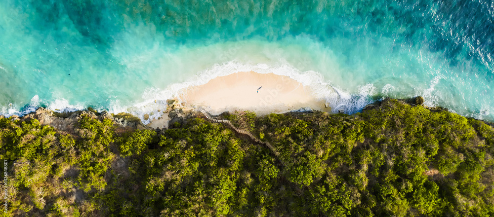Aerial view of Green Bowl Beach in Bali, Indonesia, with turquoise waves, golden sand, and tropical jungle surrounding a hidden cove.