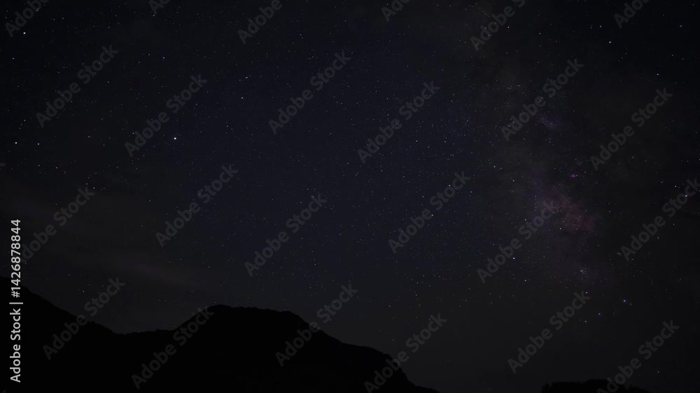 Stunning time lapse of a dreamy starry sky with clouds moving over mountains at night Stunning time lapse of a dreamy starry sky with clouds moving over mountains at night