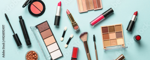 Obraz na płótnie Beauty products on blue background. Cosmetic palette, brushes, cream and lipsticks. Long banner format. w salonie