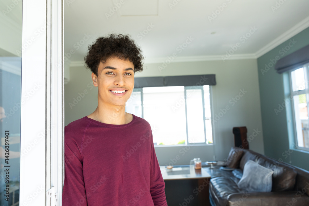 Man standing partially in sliding glass door frame in living room with large window, copy space