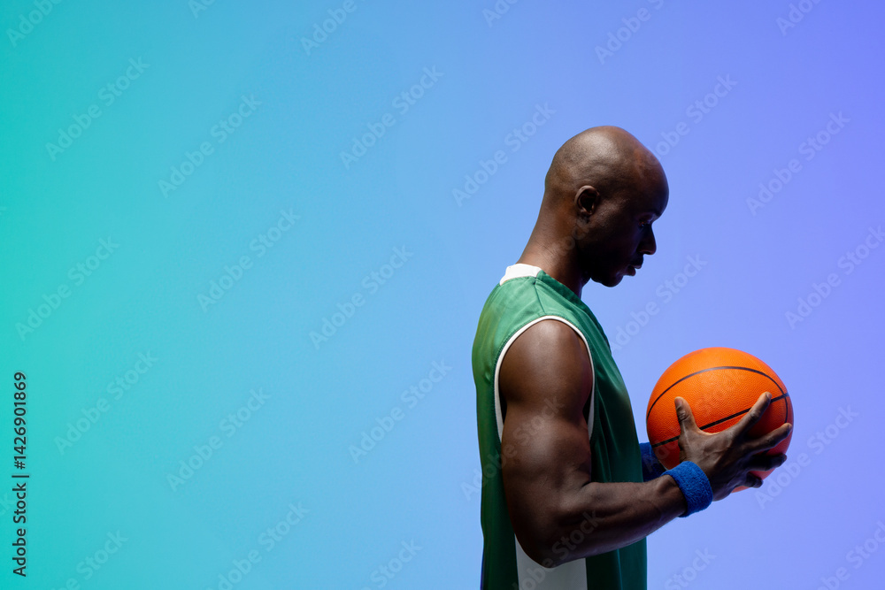 African American man holding basketball with green-white jersey against studio backdrop, copy space