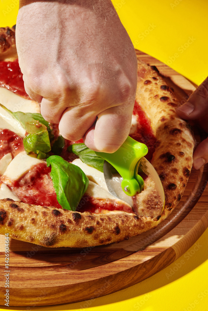 Chef cutting neapolitan pizza with wheel cutter on yellow background