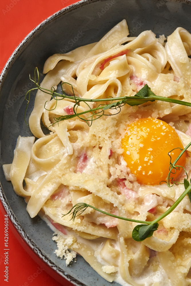 Creamy pasta carbonara with egg yolk and pea shoots garnish