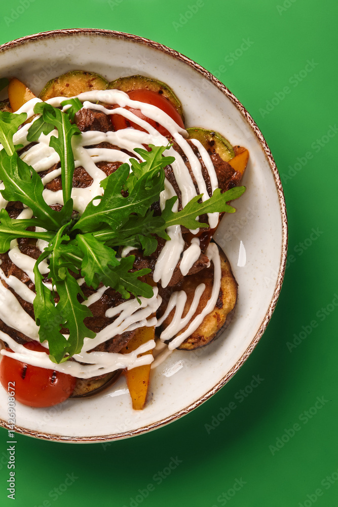 Grilled lamb with grilled vegetables and yogurt sauce on green background