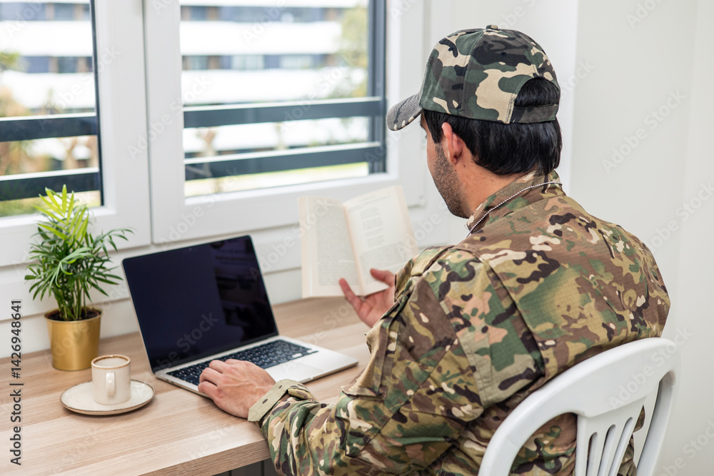 Fototapeta premium Soldier studying using laptop and reading book at home