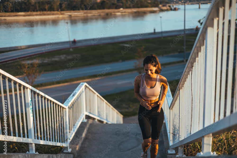 Woman Running Up Stairs During Outdoor Exercise Near Waterfront at Sunset Woman Running Up Stairs During Outdoor Exercise Near Waterfront at Sunset