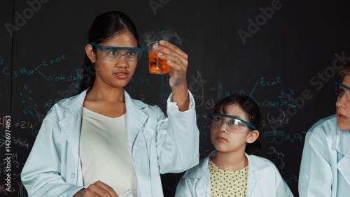 Obraz na płótnie Smart girl pour colored solution in to beaker while diverse student excited about doing experiment. Professional scientist prepare for doing experiment at blackboard with chemical theory. Edification. w salonie