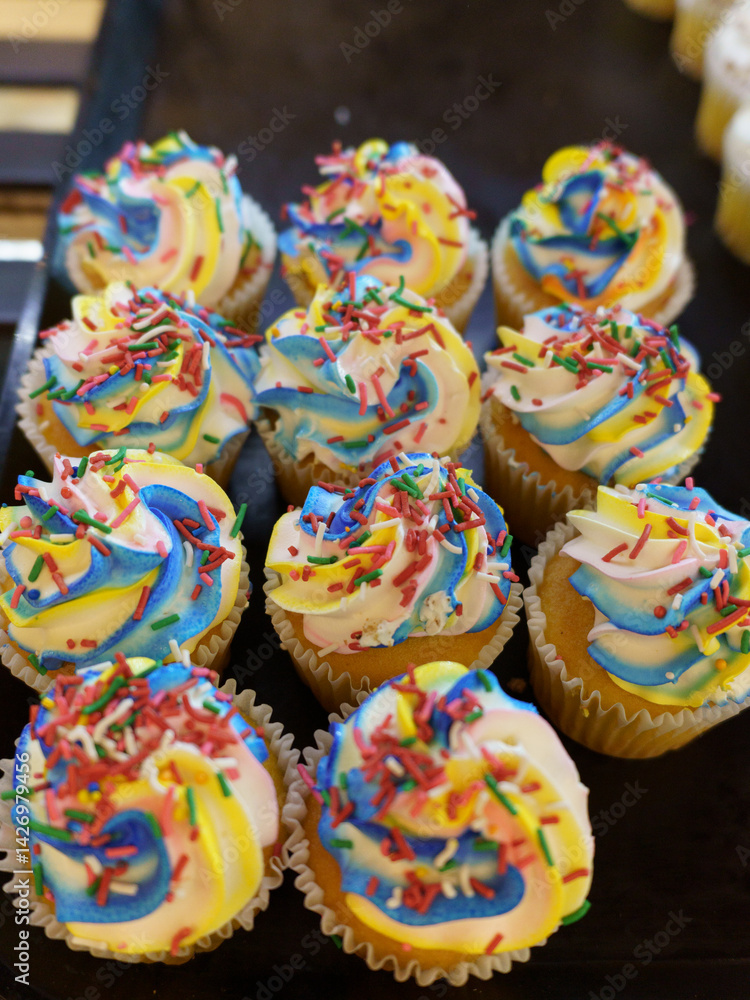Vibrant cupcakes, each swirled with rainbow frosting and topped with colorful sprinkles. Vibrant cupcakes, each swirled with rainbow frosting and topped with colorful sprinkles.