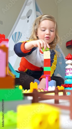 A young child and mother playing with colorful building blocks in a cozy indoor setting. Warm family bonding, creativity, and childhood development in a playful and loving home environment.