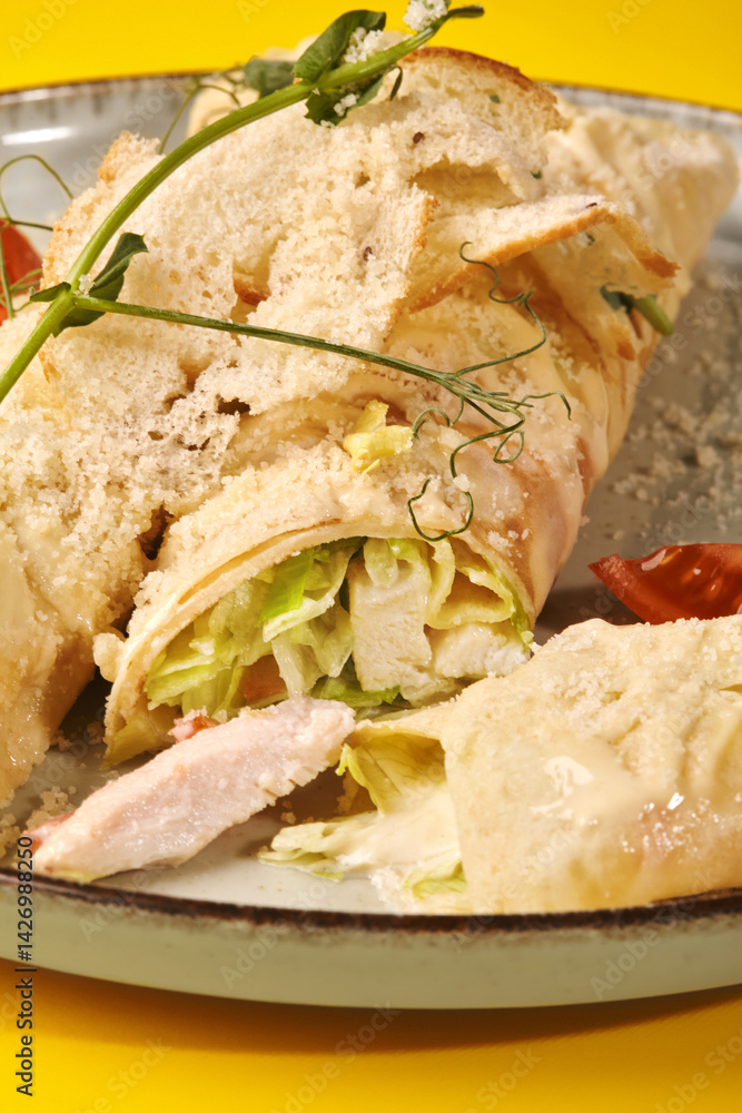 Caesar wrap with chicken, parmesan and croutons on yellow background