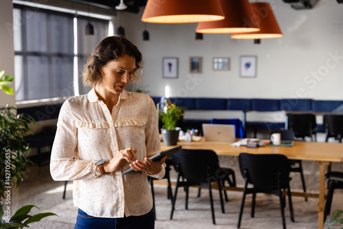 Obraz na płótnie Woman standing and holding tablet at modern coworking office, with laptop mug stylus and plants w salonie