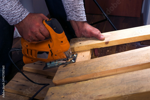 Wallpaper Mural close up of carpenter that work on woodworking using electric jigsaw for wood. Torontodigital.ca