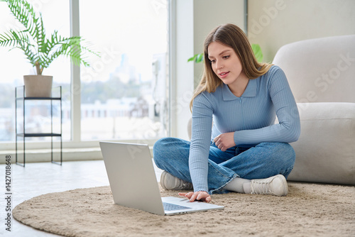 Obraz na płótnie Young woman using laptop, sitting on floor at home w salonie