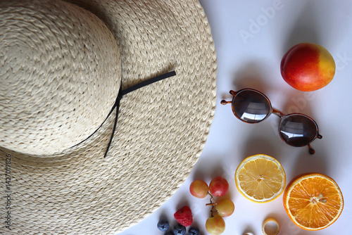 Straw hat, sunglasses, seasonal fruit, seashells and colorful accessories on white backgrounds. Cute summer essentials. Flat lay.