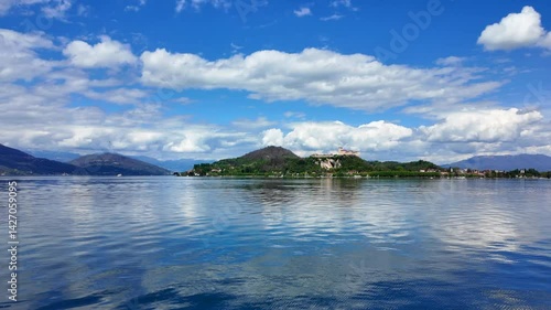 Peaceful lake with soft waves, hillside town and bright sky with clouds seen from across the water