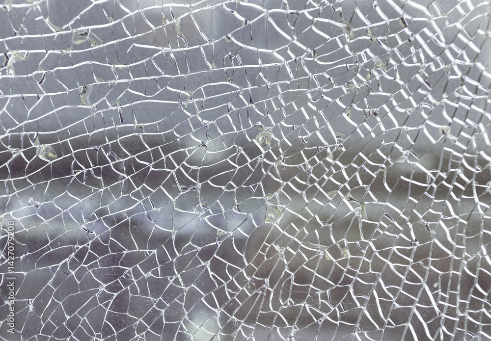 Cracks on the glass surface background. Texture of broken tempered glass pane too many small irregular shape pieces holding together. Detail of cracked broken glass cracked by impact, Space for text.