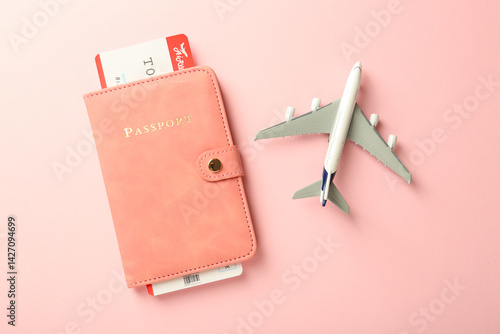 Картината върху платно Passport with ticket and plane model on pink background, flat lay
