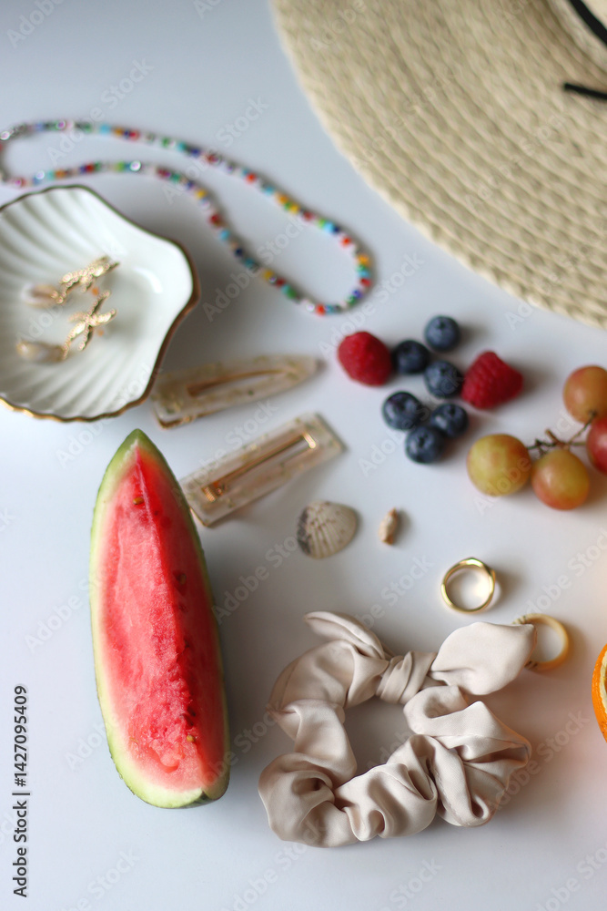 Straw hat, sunglasses, seasonal fruit, seashells and colorful accessories on white backgrounds. Cute summer essentials. Selective focus.