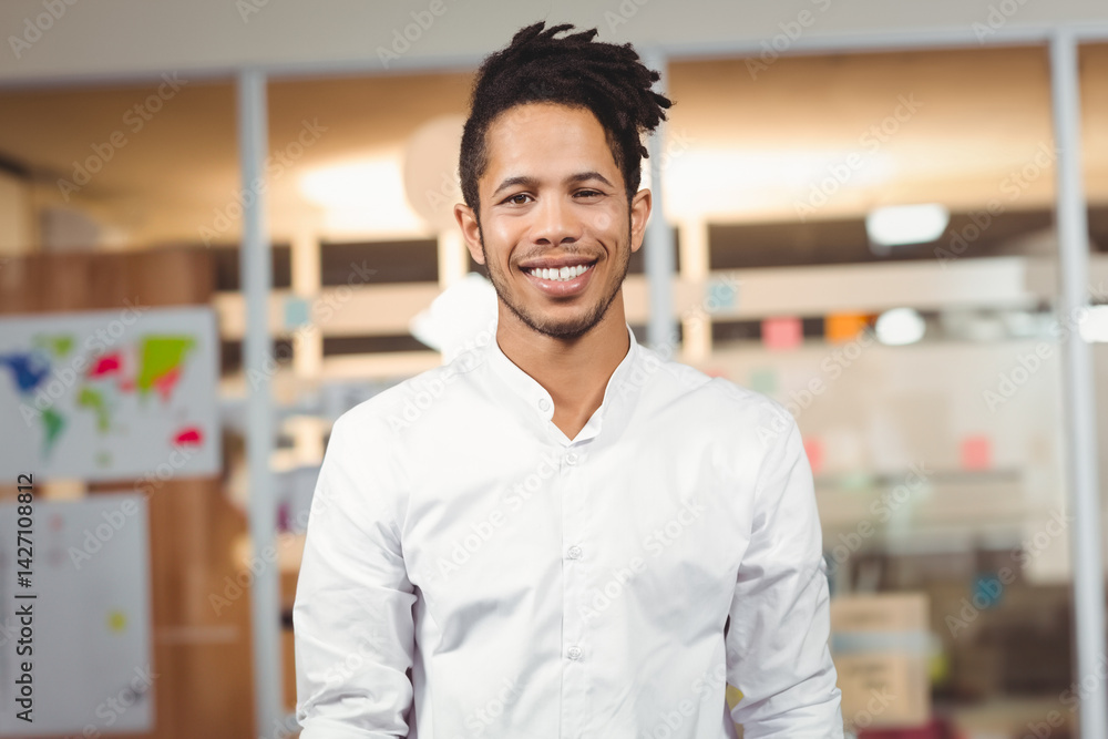 African American man standing and smiling in office with glass partitions and colorful sticky notes