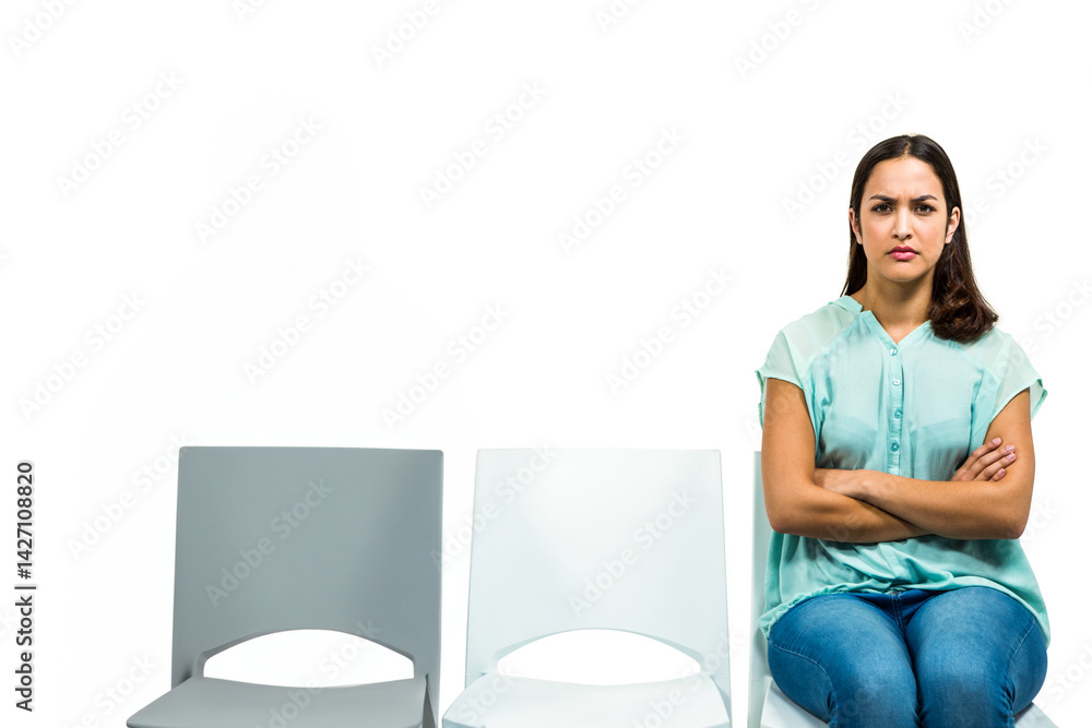 Woman sitting on plastic chairs in empty studio, crossing arms, legs with stern look, copy space