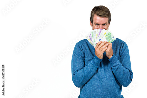 Obraz na płótnie Man holding euro banknotes over face in studio, showing playful expression, copy space w salonie