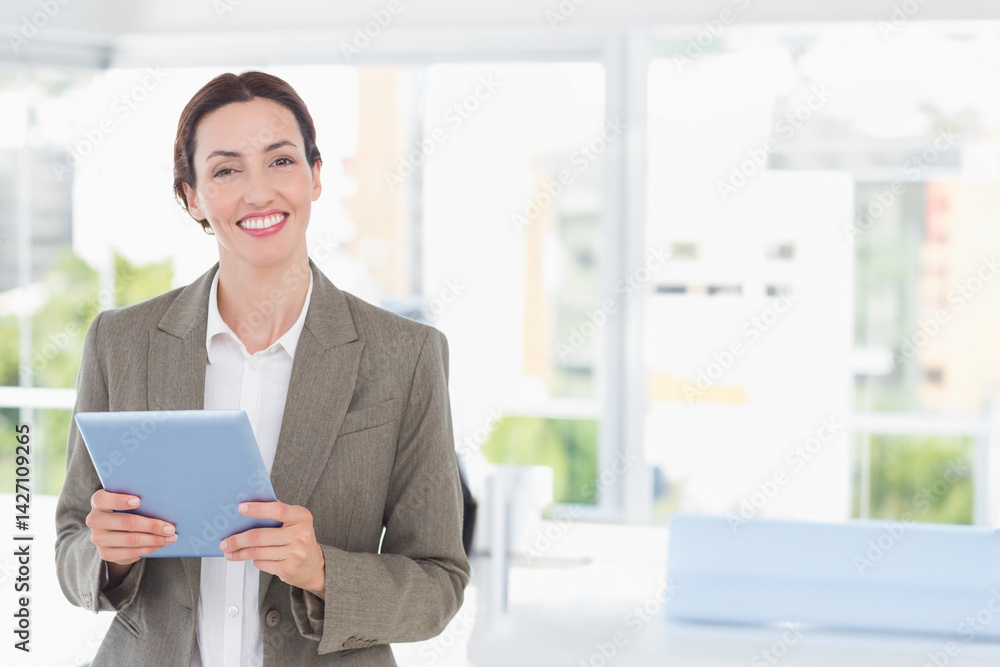 Woman holding light blue tablet in modern bright office, with natural light theme, copy space