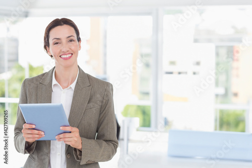 Obraz na płótnie Woman holding light blue tablet in modern bright office, with natural light theme, copy space w salonie