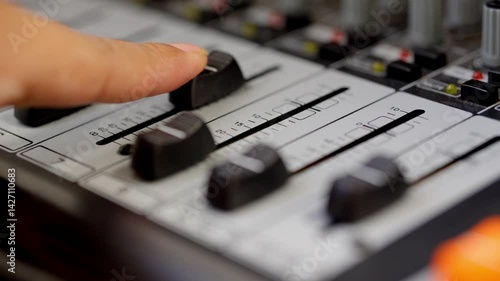 A sound engineer equalizes sound on a sound board, turning up volume levels. Multimedia recording workspace