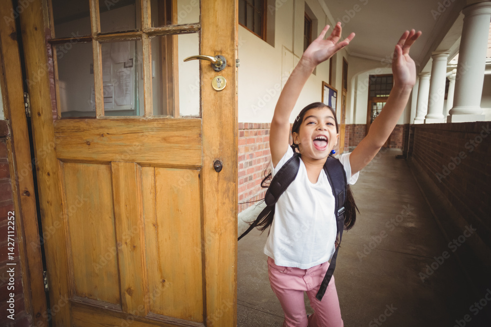 Obraz premium Schoolgirl bursting through wooden door into long tiled corridor, with dark backpack, copy space