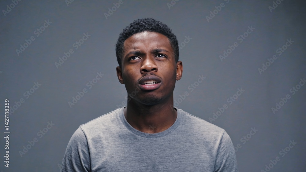 Obraz premium A young man with a surprised or contemplative expression, looking to the side.