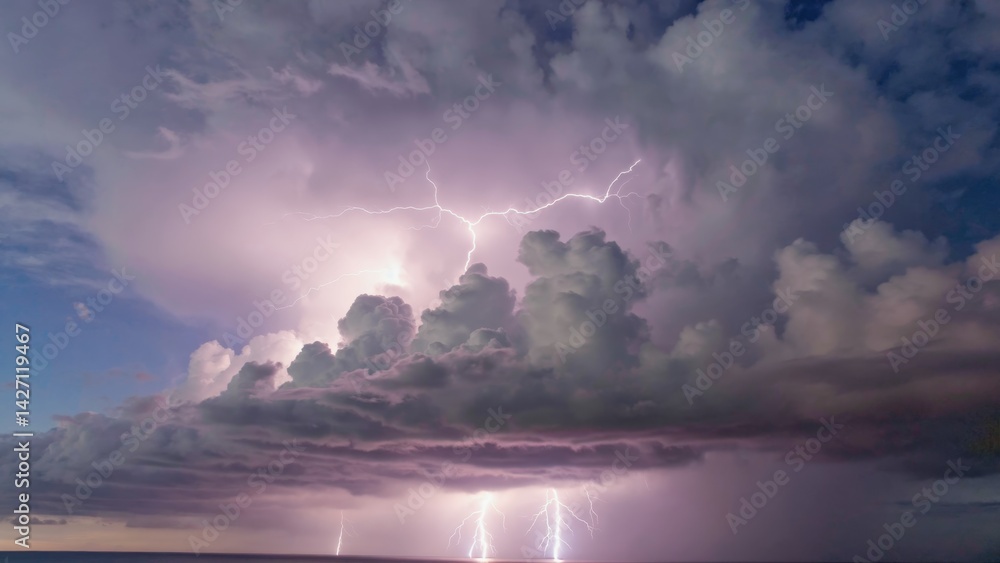 A dramatic nighttime image of powerful thunderstorm clouds with multiple bright lightning strikes against the dark sky.