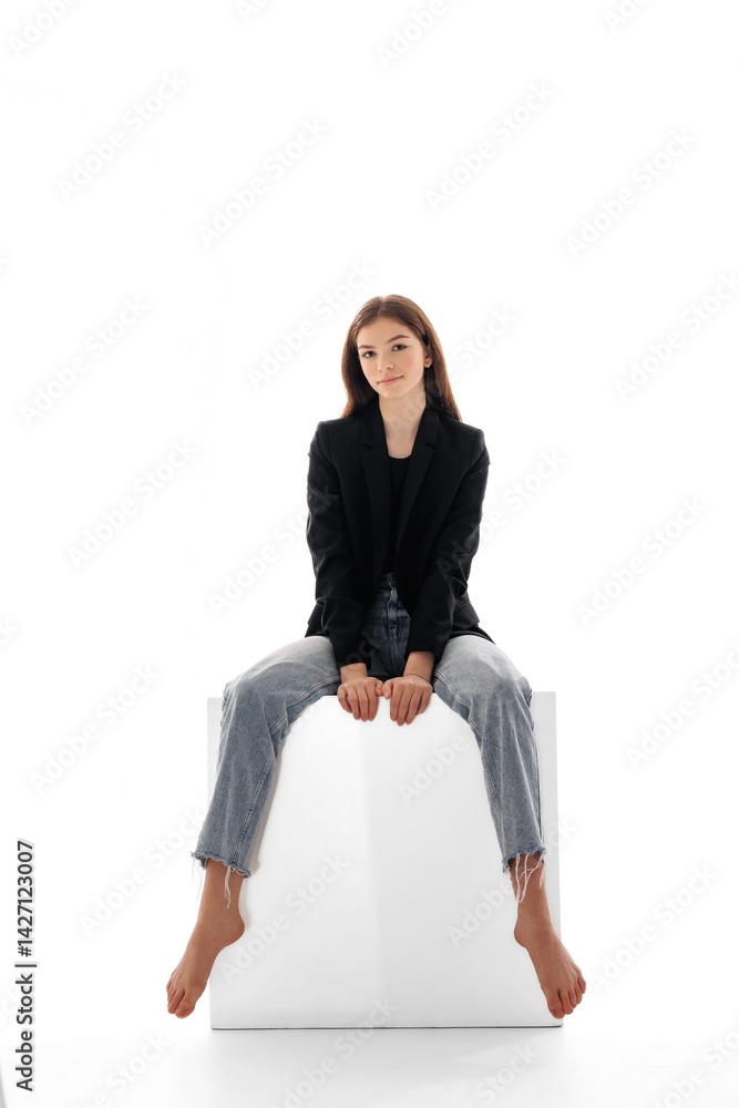 Model in stylish outfit poses on white cube in studio during photoshoot showcasing confidence and beauty Model in stylish outfit poses on white cube in studio during photoshoot showcasing confidence and beauty