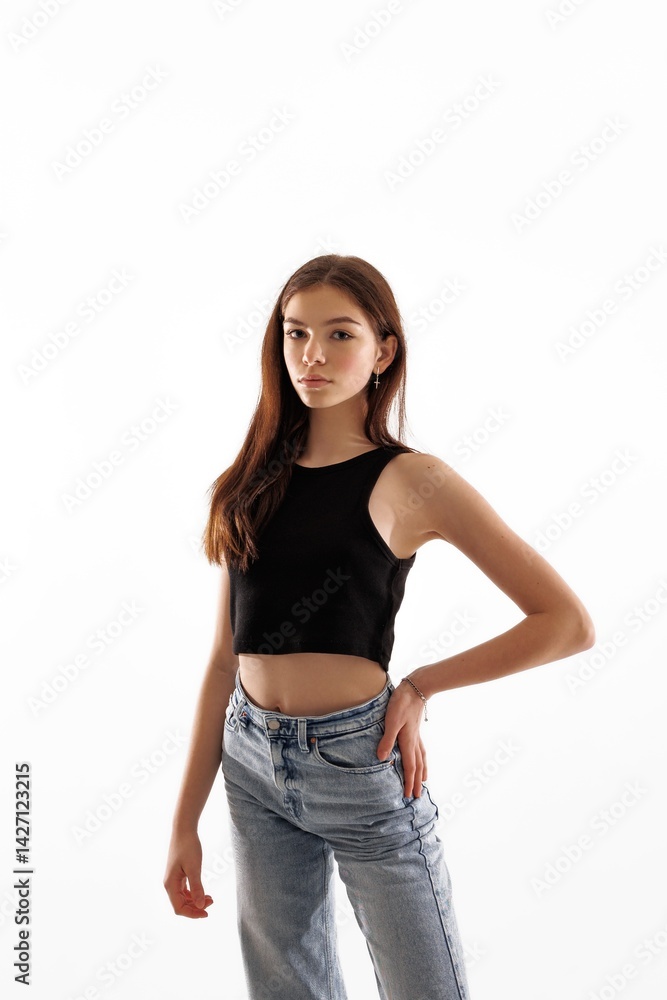Young model poses confidently against a plain background in casual attire in a photography studio Young model poses confidently against a plain background in casual attire in a photography studio