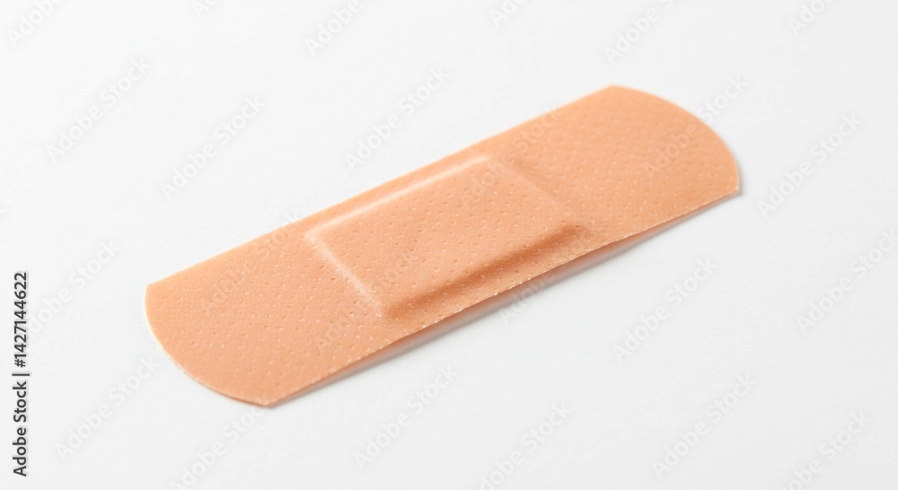 A single adhesive bandage on a white surface used for first aid and wound care applications and healing A single adhesive bandage on a white surface used for first aid and wound care applications and healing