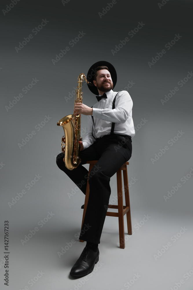 Naklejka premium Professional musician with saxophone on grey background, low angle view