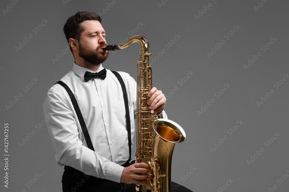 Fototapeta premium Professional musician playing saxophone on grey background. Space for text