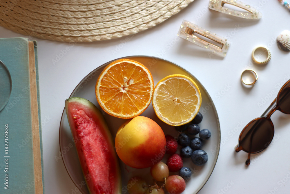Glass of cocktail, straw hat, sunglasses, books, fresh fruit, chocolate and accessories. Summer essentials on the table. Top view.