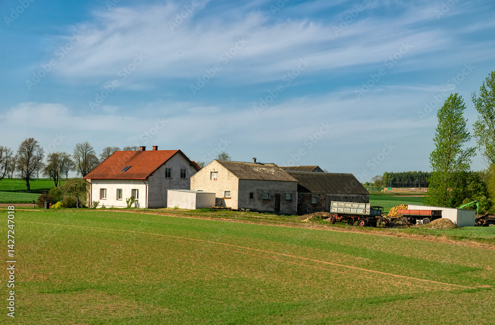 Old farm among green sown fields. Agriculture in Europe Old farm among green sown fields. Agriculture in Europe
