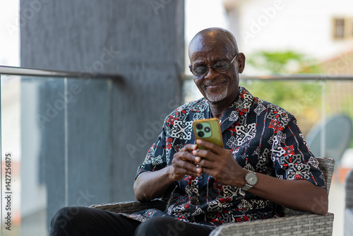 Elderly African man uses his smartphone for internet banking sending money.