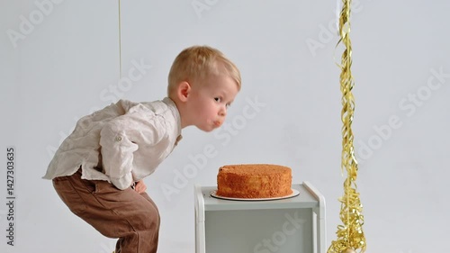 Smiling three-year-old bites cake in white studio, capturing a sweet, playful food moment.
