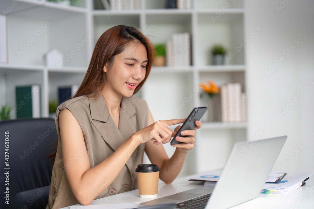 Communication and Technology. A young woman engaged in mobile communication while enjoying coffee in her organized workplace. Communication and Technology. A young woman engaged in mobile communication while enjoying coffee in her organized workplace.