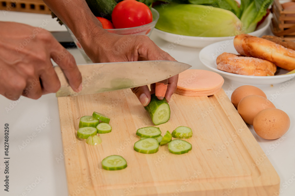 Asian man with beard sitting makes sandwich and divide two peice with knife in kitchen for breakfast in morning. Male wear apron enjoy make food for health care in house, healthy food at home. Asian man with beard sitting makes sandwich and divide two peice with knife in kitchen for breakfast in morning. Male wear apron enjoy make food for health care in house, healthy food at home.