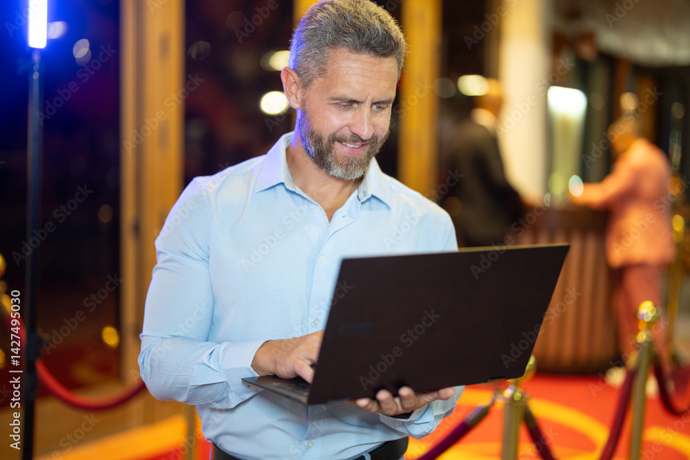 Business man using a laptop on street at night. Business man planning work on laptop outdoors. Business man browsing on a laptop under neon city lights. Freelancer businessman. Night business.