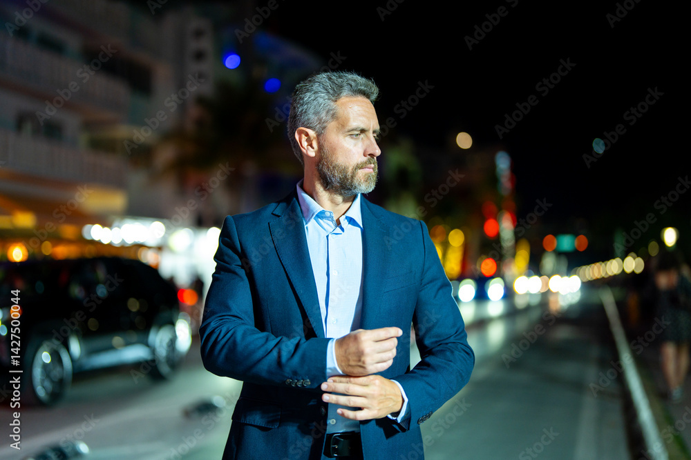 Successful businessman posing at night city. Rich businessman in a suit standing in the night street. Handsome businessman in a formal suit. Stylish businessman. Elegant business man.