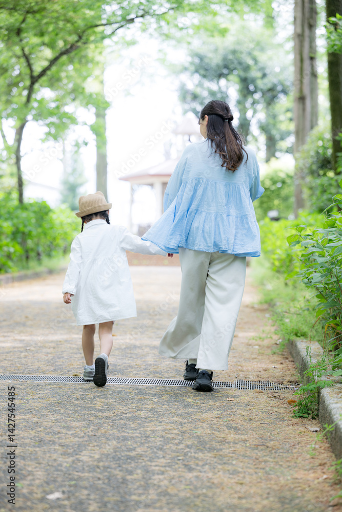 Fototapeta premium 公園で手を繋いで歩く母娘の後ろ姿