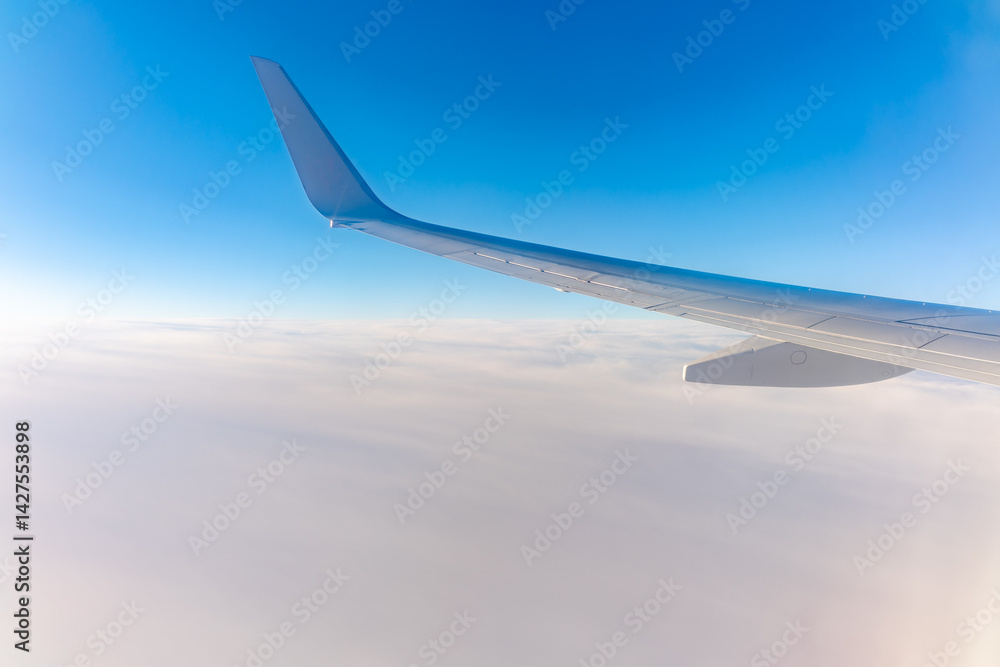 Fototapeta premium View from the airplane window at a beautiful cloudy sky and the airplane wing