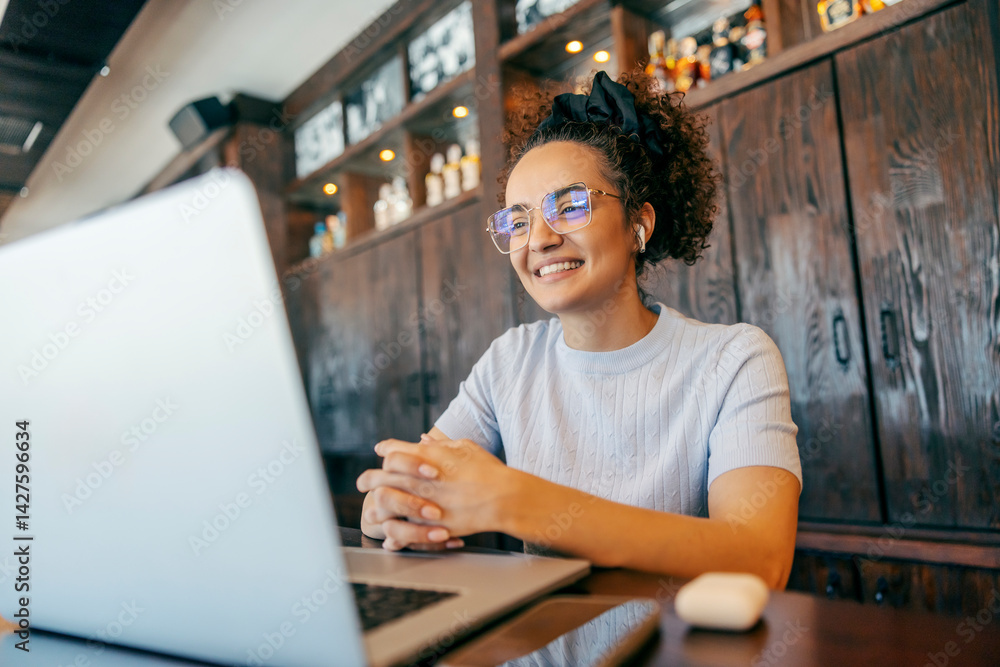 Portrait of freelancer having conference call on laptop in working friendly coffee shop.