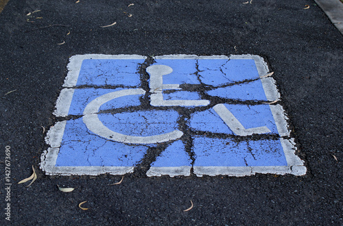Damaged and cracked Handicapped Parking sign painted on an asphalt road