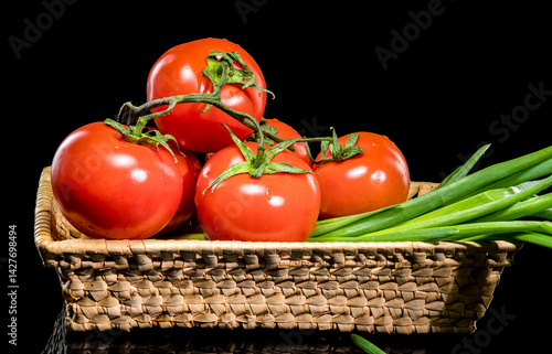 Obraz na płótnie Fresh Tomatoes in Basket with Green Onions on Black Background w salonie