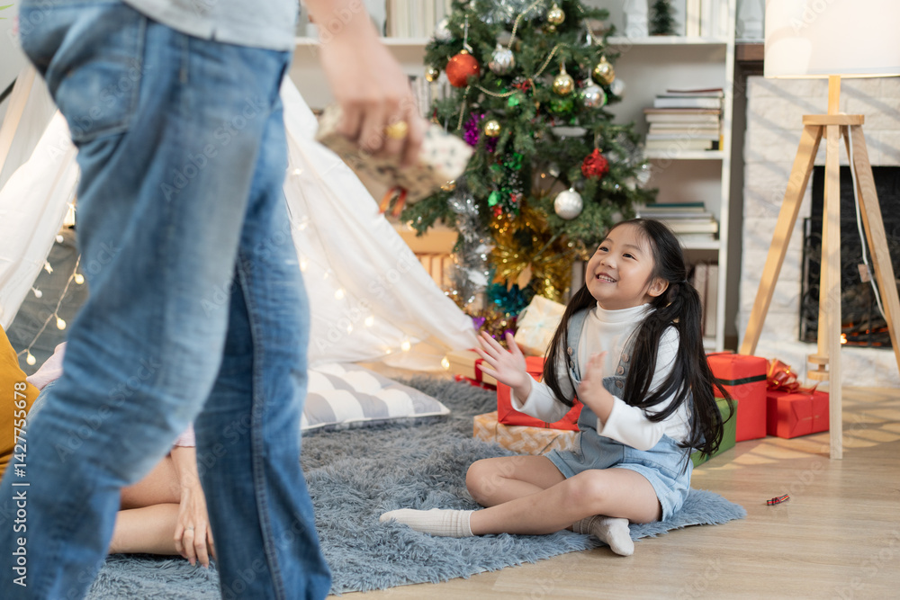 Asian daughter sitting on floor applauding and enjoy playing with family in the living room at home Asian daughter sitting on floor applauding and enjoy playing with family in the living room at home